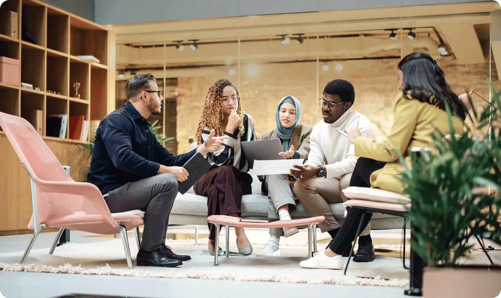 Five colleagues from different backgrounds discuss a document in an office